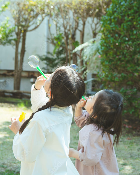 庭でシャボン玉遊びをする姉妹