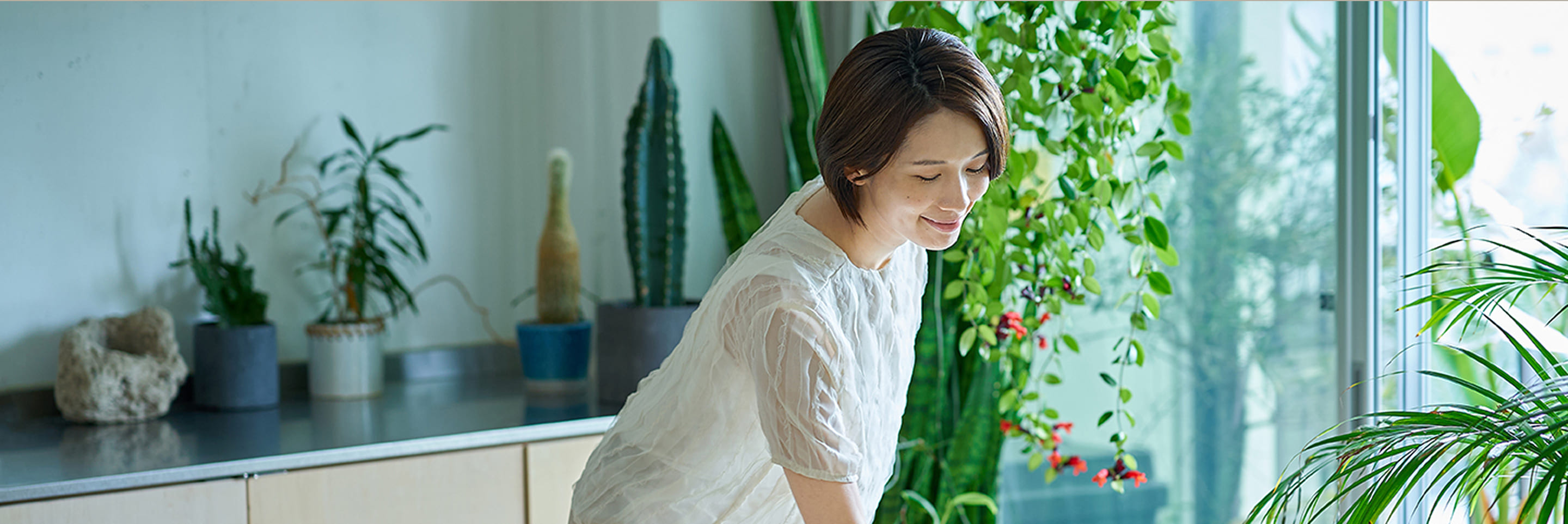 観葉植物に囲まれた部屋で微笑む女性